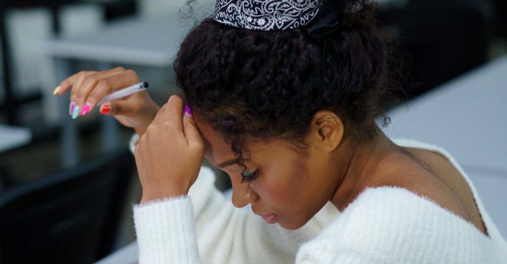 A young woman deeply concentrating while sitting at a desk with study materials.